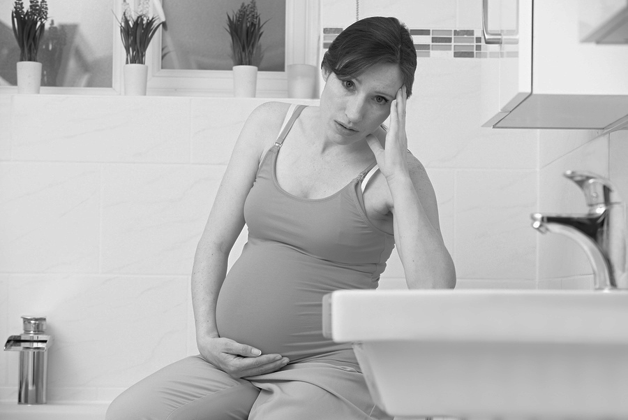 Pregnant Woman Suffering With Morning Sickness In Bathroom